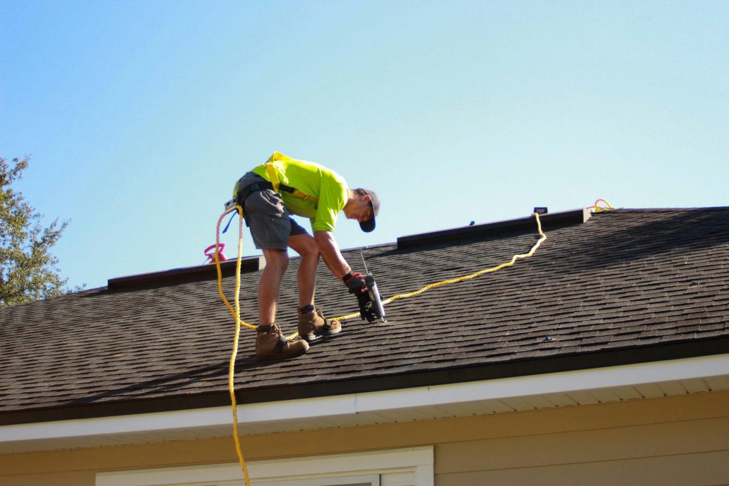 a man working on a roof with a power drill (Symbolbild: Solarausbau Großstädte)