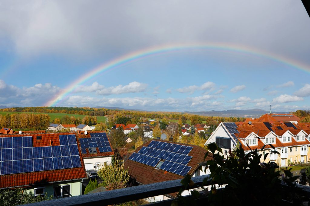 Rainbow over a suburban neighborhood with solar panels (Symbolbild: Photovoltaik)